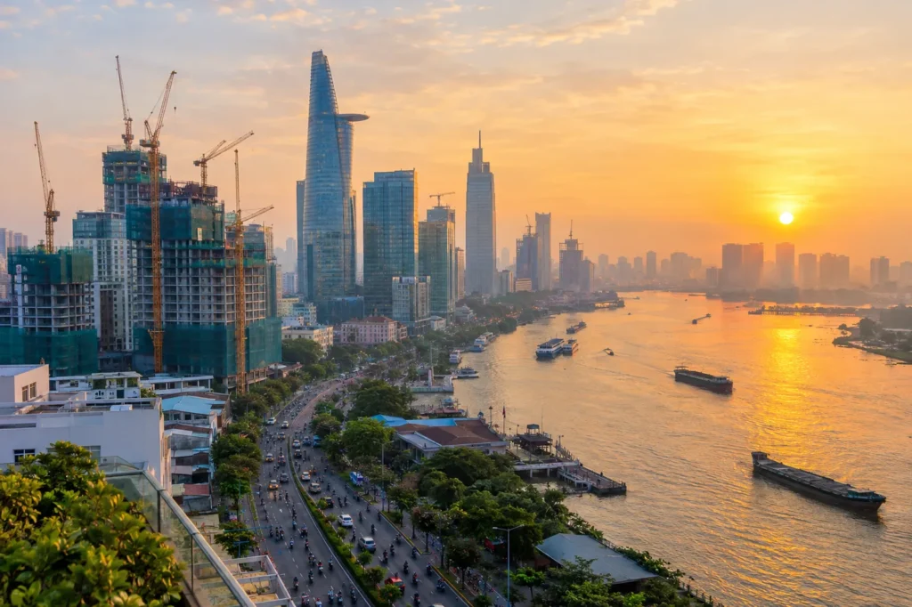 Fast-growing Southeast Asian city at sunrise with construction cranes and a busy river