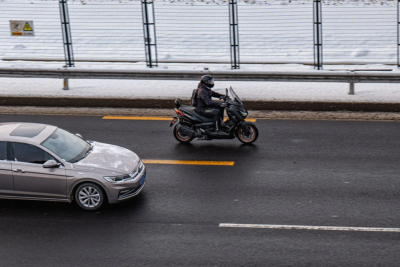 Honda ADV350 alternative: a maxi-scooter riding next to a car on a city road