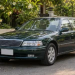Buying an Old Car: Why I Want One Built Like a Tank Well-kept older dark green sedan parked on a quiet tree-lined street, an example of buying an old car