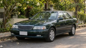 Well-kept older dark green sedan parked on a quiet tree-lined street, an example of buying an old car