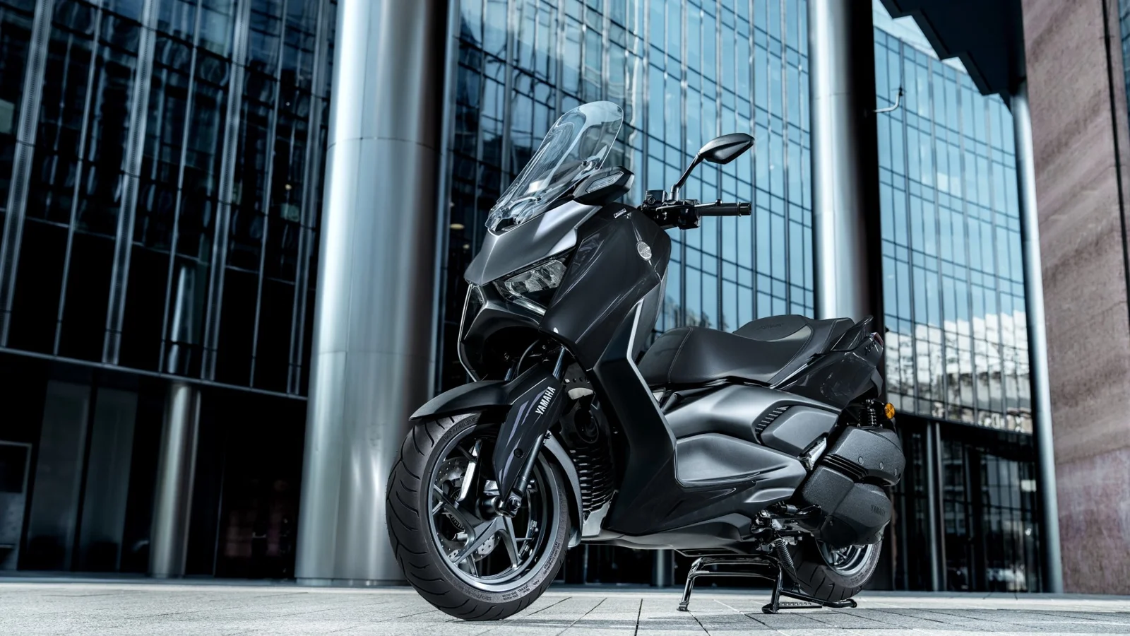 Yamaha XMAX, a Honda ADV350 alternative sold in the US, parked in front of a glass building